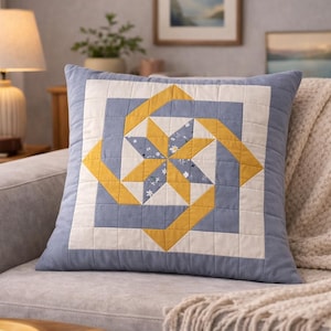 Könnte beinhalten: Dekoratives quadratisches Kissen mit Patchwork-Design. Das Kissen hat ein zentrales Sternmuster in Gelb, Weiß und Blau auf hellblauem Hintergrund. Das Kissen liegt auf einem grauen Sofa mit einer cremefarbenen Decke.