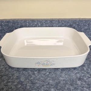 May include: White rectangular baking dish with handles. The dish has a floral design in blue, yellow, and red. The dish is made of a durable material and is suitable for baking and serving.