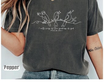 Könnte beinhalten: Dunkelgraues T-Shirt mit einer weißen Strichzeichnung von drei Vögeln auf einem Ast. Darunter steht der Text "I will sing of the goodness of god, PSALM 89:1". Das Shirt ist mit "Pepper" gekennzeichnet.