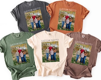 Könnte beinhalten: Fünf kurzärmelige T-Shirts mit Rundhalsausschnitt in Anthrazit, gebranntem Orange, Olivgrün, Creme und Braun. Jedes Shirt zeigt einen rechteckigen Grafikdruck einer vierköpfigen Familie mit Hund im Freien, mit dem Text CUSTOM PHOTO darüber.