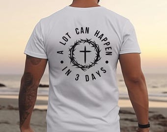 Könnte beinhalten: Weißes T-Shirt mit schwarzem Aufdruck auf dem Rücken. Die Grafik zeigt ein Kreuz in einem Dornenkranz, mit dem Text "A LOT CAN HAPPEN IN 3 DAYS", der das Design umgibt. Das T-Shirt ist schlicht und einfach.
