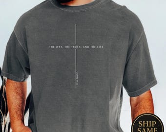 Könnte beinhalten: Dunkelgraues T-Shirt mit dem Text "THE WAY, THE TRUTH, AND THE LIFE" und einer vertikalen Linie, die ein Kreuz bildet. Darunter steht "JOHN 14:6". Das Shirt ist einfarbig und hat kurze Ärmel.