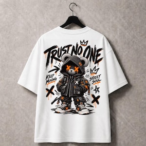 Puede incluir: Una camiseta blanca de manga corta con el gráfico de un oso con chaqueta con capucha y zapatillas. El oso tiene cruces naranjas sobre los ojos. El texto dice TRUST NO ONE, KEEP MOVING y STREET SOUL en negro, con detalles en naranja.