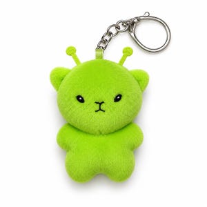 May include: A bright lime green plush keychain shaped like a small creature with two antennae on its head. The plush features embroidered black eyes and a small black mouth. A silver metal chain and a circular keyring are attached to the top.