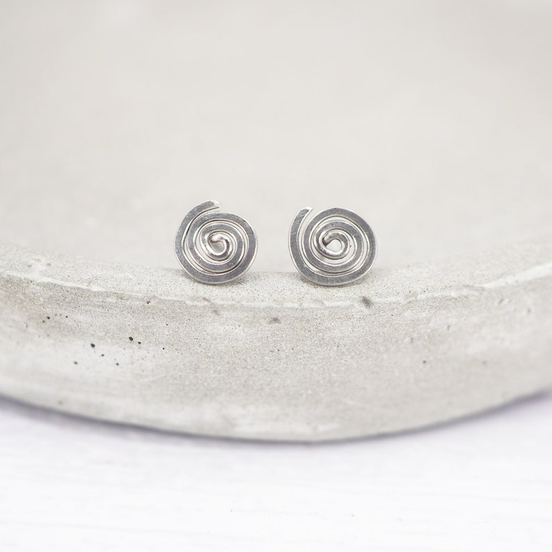 Spiral-shaped grade 1 titanium wire stud earrings. They are made from a continuous piece of 0.8mm wire. The spirals measure around 8mm across but may vary slightly due to being handmade.