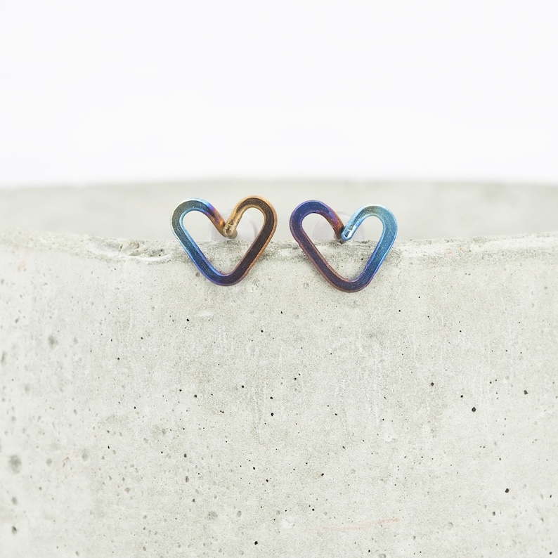 Anodised heart-shaped grade 1 titanium wire stud earrings. They are made from a continuous piece of 0.8mm wire. The hearts measure around 8mm across but may vary slightly due to being handmade. Blue, Yellow and purple tones.