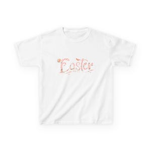 May include: White t-shirt featuring the word "Easter" in a floral design. The text is in a cursive font with pink, orange, and green floral accents. The shirt has a crew neck and short sleeves.