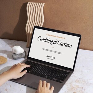 Può includere: Un computer portatile grigio scuro che mostra sullo schermo il testo Ti do il benvenuto al percorso di Coaching di Carriera, seguito da Un percorso strutturato per costruire la tua prossima mossa professionale con chiarezza e strategia, e Anna Rossi.