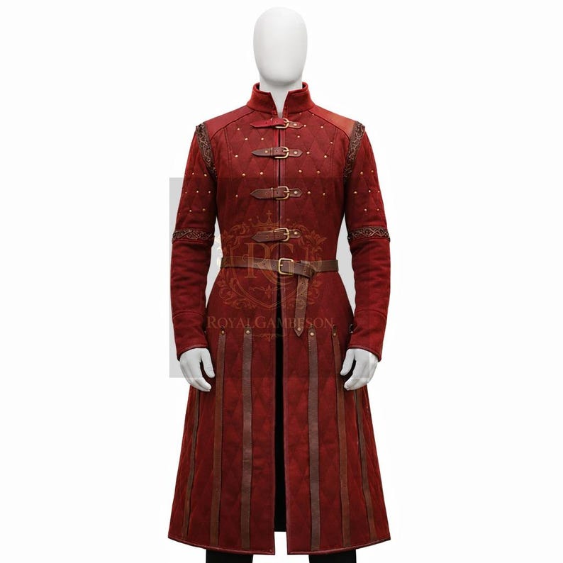 May include: A long, red coat with a high collar, three buckle closures, and a belt. The coat features decorative stitching, gold-colored studs, and vertical brown leather accents. The coat is displayed on a mannequin.