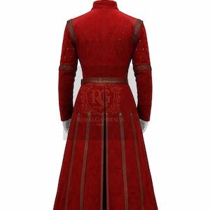 May include: A long, red quilted coat with brown leather accents and a matching belt. The coat features a high collar, decorative stitching, and vertical leather stripes on the skirt. The back of the coat is visible on a mannequin.