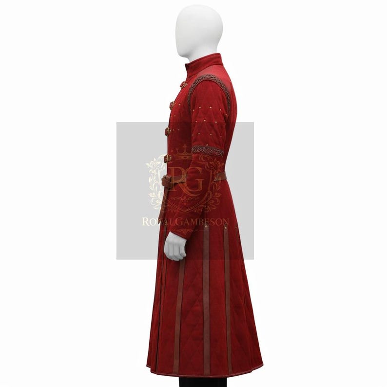 May include: A long, red coat with a high collar and decorative gold buttons. The coat features brown leather accents, a belt, and vertical stitched panels. The text "ROYALGAMBESON" is visible on the lower portion of the coat.
