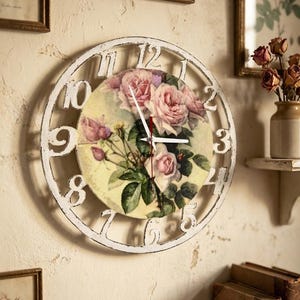 Peut inclure: Horloge murale blanche vieillie avec un motif de roses. Le cadran de l'horloge présente un bouquet de roses roses et de feuilles vertes. Les chiffres sont dans une police classique. L'horloge est fixée sur un mur beige.