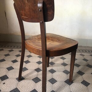 May include: A vintage wooden chair with a curved back and seat. The chair is made of dark brown wood and has a classic design. The chair's legs are slender and slightly angled, and the seat shows signs of wear.
