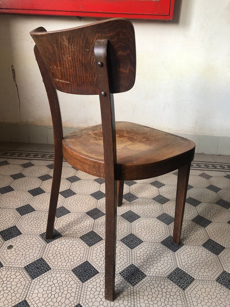 May include: A vintage wooden chair with a curved back and seat. The chair is made of dark brown wood and has a classic design. The chair's legs are slender and slightly angled, and the seat shows signs of wear.