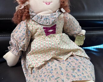 Cloth doll with brown  curly hair wearing brown floral dress and bonnet