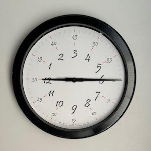 May include: A white ceramic mug with a black handle and the text "But First, Coffee" in a bold, black font. The mug is set against a blurred background, suggesting a cozy setting.