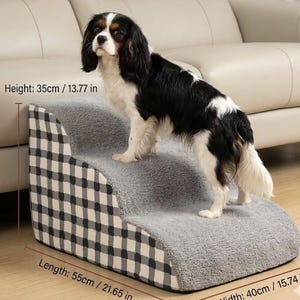 May include: A two-step pet stair in gray plush fabric with a black and white checkered side panel. The pet step measures 21.65 inches long, 15.74 inches wide, and 13.77 inches high. A Cavalier King Charles Spaniel dog is standing on the top step.