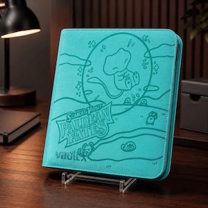 May include: A teal-colored zippered trading card binder featuring an embossed illustration of a small creature inside a circular bubble. The cover displays the text Scarlet & Violet Paldean Fates and the Vault X logo in a dark teal outline.
