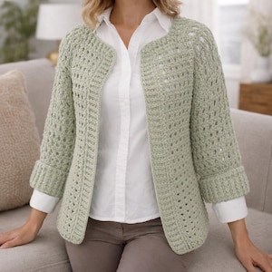 Op de afbeelding: Een lichtgroen gehaakt vest met open voorkant en driekwartmouwen. Het vest heeft een textuurpatroon en omgeslagen manchetten. Het wordt gedragen over een wit overhemd en een bruine broek. Een comfortabel en stijlvol kledingstuk.