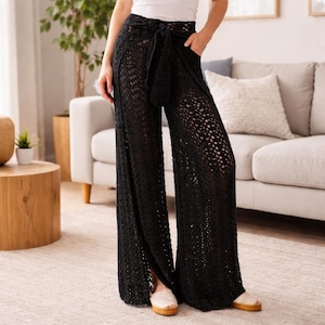 May include: Black crochet wide-leg pants with a matching tie belt. The pants have a high waist and pockets. The open weave design allows for a peek-through effect. The pants are worn with a white top and tan shoes.