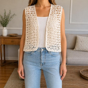 Peut inclure: Un gilet en crochet crème à devant ouvert avec un motif floral. Le gilet sans manches est porté sur un débardeur blanc et un jean bleu clair. Le gilet est un vêtement léger et respirant, parfait pour la superposition.