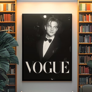 May include: Black and white Vogue poster featuring a portrait of a man in a tuxedo and bow tie. The poster is displayed above a bench in a room with bookshelves on either side. The word "VOGUE" is prominently displayed.