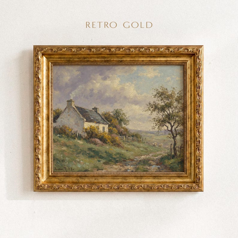 Vintage oil painting of a white stone cottage with a gray roof on a green hillside, surrounded by flowering bushes, a lone tree, and a dirt path under a cloudy sky, displayed in an ornate gold frame.