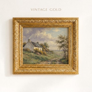 Vintage oil painting of a white stone cottage with a gray roof on a green hillside, surrounded by flowering bushes, a lone tree, and a dirt path under a cloudy sky, displayed in an ornate gold frame.