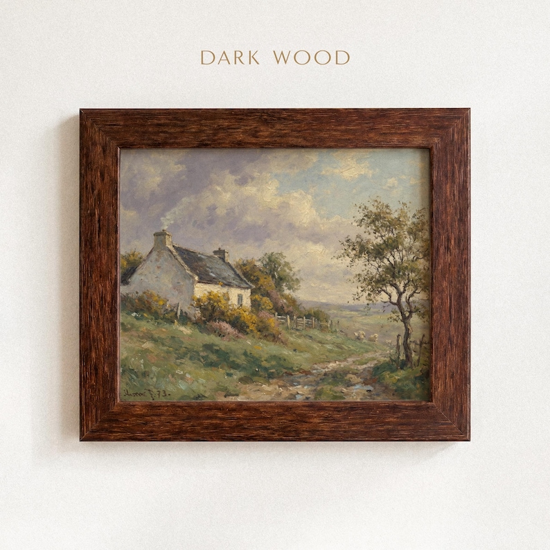 Vintage oil painting of a white stone cottage with a gray roof on a green hillside, surrounded by flowering bushes, a lone tree, and a dirt path under a cloudy sky, displayed in an ornate gold frame.