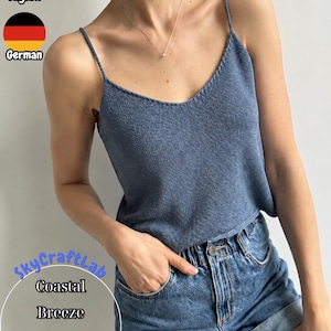 May include: A blue knit camisole featuring thin spaghetti straps and a V-neckline. The garment has a textured, woven appearance and is paired with blue denim shorts. The text SkycraftLab Coastal Breeze Knit Camisole is visible.