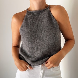 May include: A gray sleeveless knit top with a high neckline and a halter style. The top is made of a soft, lightweight fabric and has a relaxed fit.