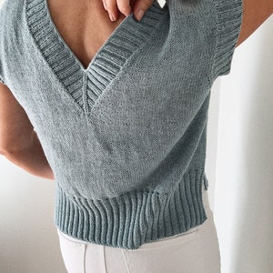 May include: A light blue knitted top with a V-neck and short sleeves.