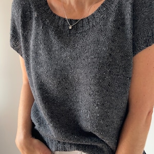May include: A grey knitted top with short sleeves and a scoop neck. The top is made from a soft, textured yarn.