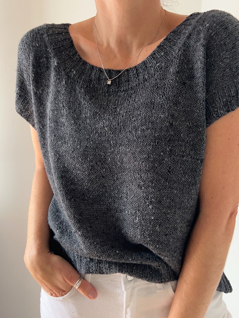 May include: A grey knitted top with short sleeves and a scoop neck. The top is made from a soft, textured yarn.
