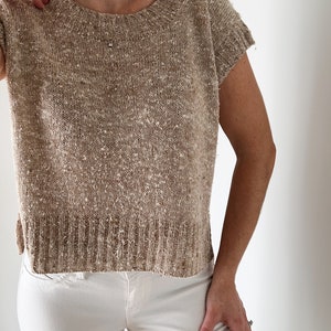 May include: A beige knitted top with short sleeves. The top has a speckled texture and a round neckline.