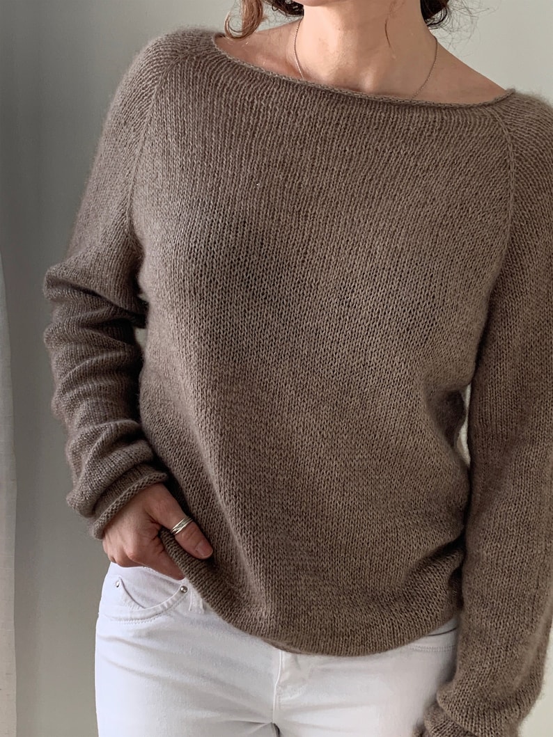 May include: A brown knitted sweater with a wide neckline and long sleeves.