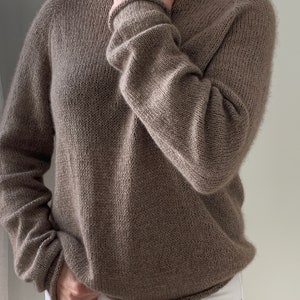 May include: A brown knitted jumper with a loose fit and long sleeves.