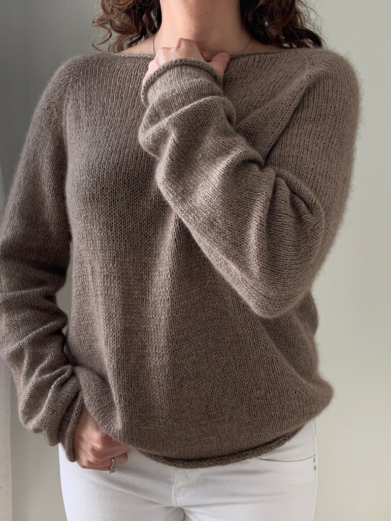 May include: A brown knitted jumper with a loose fit and long sleeves.