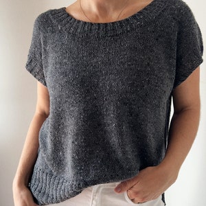 May include: A grey short-sleeved knitted top with a scoop neck.