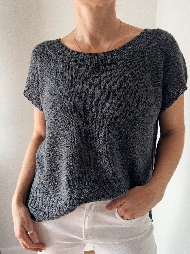 May include: A grey short-sleeved knitted top with a scoop neck.