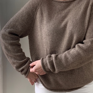 May include: A brown knitted jumper with long sleeves and a relaxed fit.