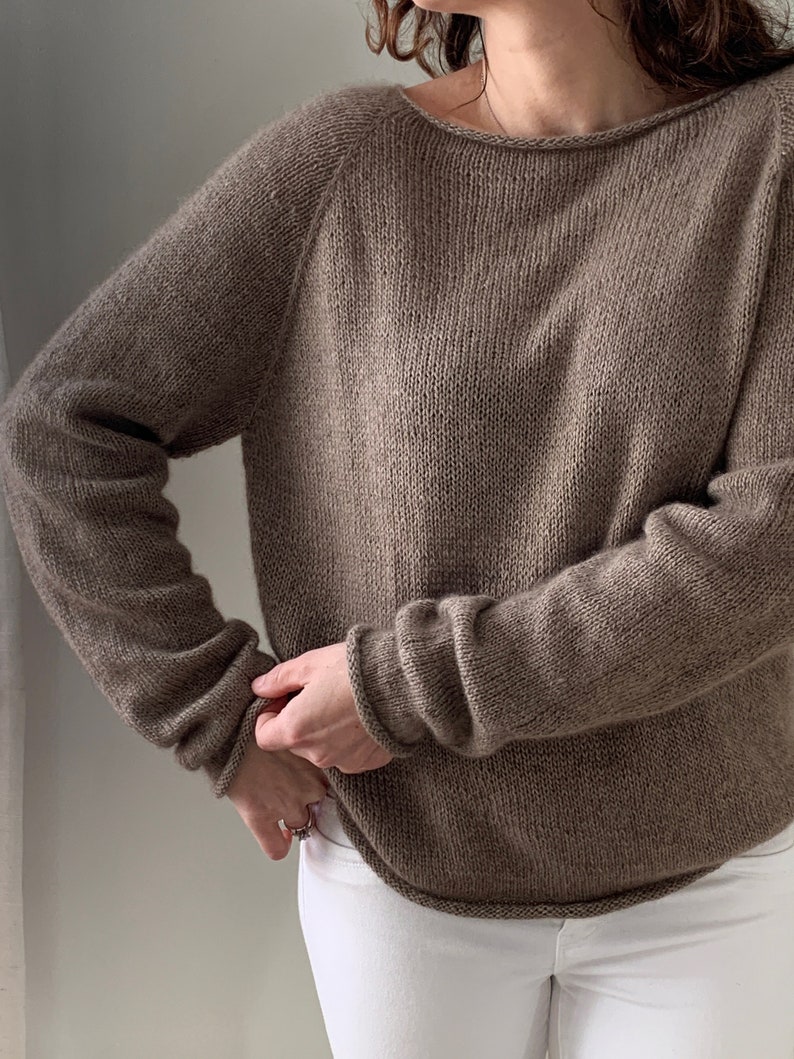 May include: A brown knitted jumper with long sleeves and a relaxed fit.
