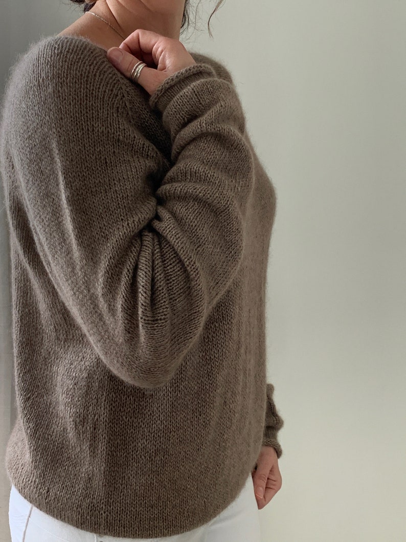 May include: A brown knitted jumper with long sleeves and a scoop neck.
