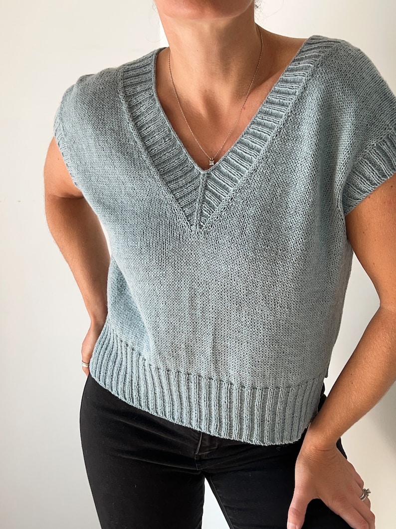 May include: A light blue knitted sleeveless top with a v-neck and a ribbed hem.