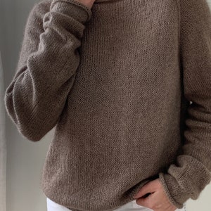 May include: A brown knitted jumper with a wide neckline and long sleeves.