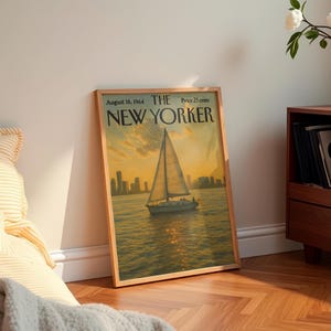 May include: A framed vintage "The New Yorker" magazine cover from August 16, 1964, featuring a sailboat on the water at sunset. The artwork has a warm color palette with a cityscape in the background.