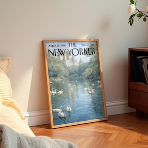 May include: A framed vintage New Yorker magazine cover from August 16, 1964, featuring a serene lake scene with swans. The cover art depicts a body of water with several white swans, trees, and buildings in the background. The magazine title and date are visible.