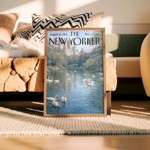 May include: A framed vintage New Yorker magazine cover from August 16, 1964, featuring a serene lake scene with swans. The cover art is set in a wooden frame, resting on a neutral-toned rug. The magazine's title and price are visible.