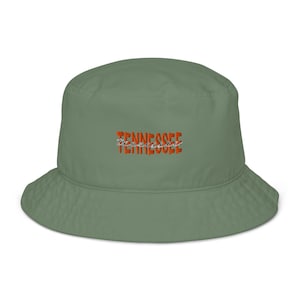 Peut inclure: Un chapeau bob vert sauge avec le mot "Tennessee" en script orange et blanc. Le chapeau a une couronne arrondie et un bord incliné vers le bas. Le chapeau est fait d'une matière douce, peut-être biologique.