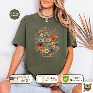 Puede incluir: Camiseta verde militar con un diseño floral y el texto "TRUST IN THE LORD WITH ALL YOUR HEART" y "PROVERBIOS 3:5". El diseño incluye flores coloridas en tonos azules, naranjas y amarillos. La camiseta está hecha de material Gildan Softstyle.